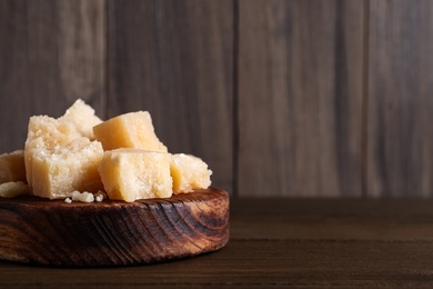 Pieces of delicious parmesan cheese on wooden table. Space for text