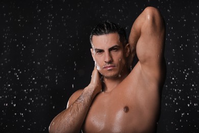 Photo of Man washing hair while taking shower on black background