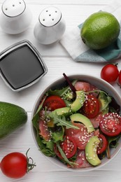 Tasty soy sauce, bowl with salad and ingredients on white wooden table, flat lay