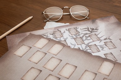 Photo of Papers with family tree templates, pencil and glasses on wooden table, closeup