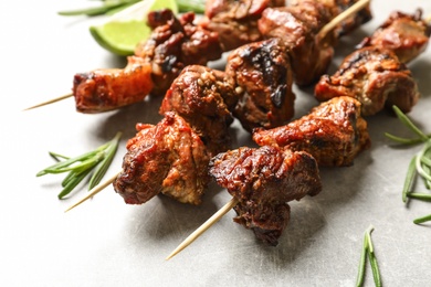 Photo of Delicious barbecued meat with rosemary on grey background, closeup