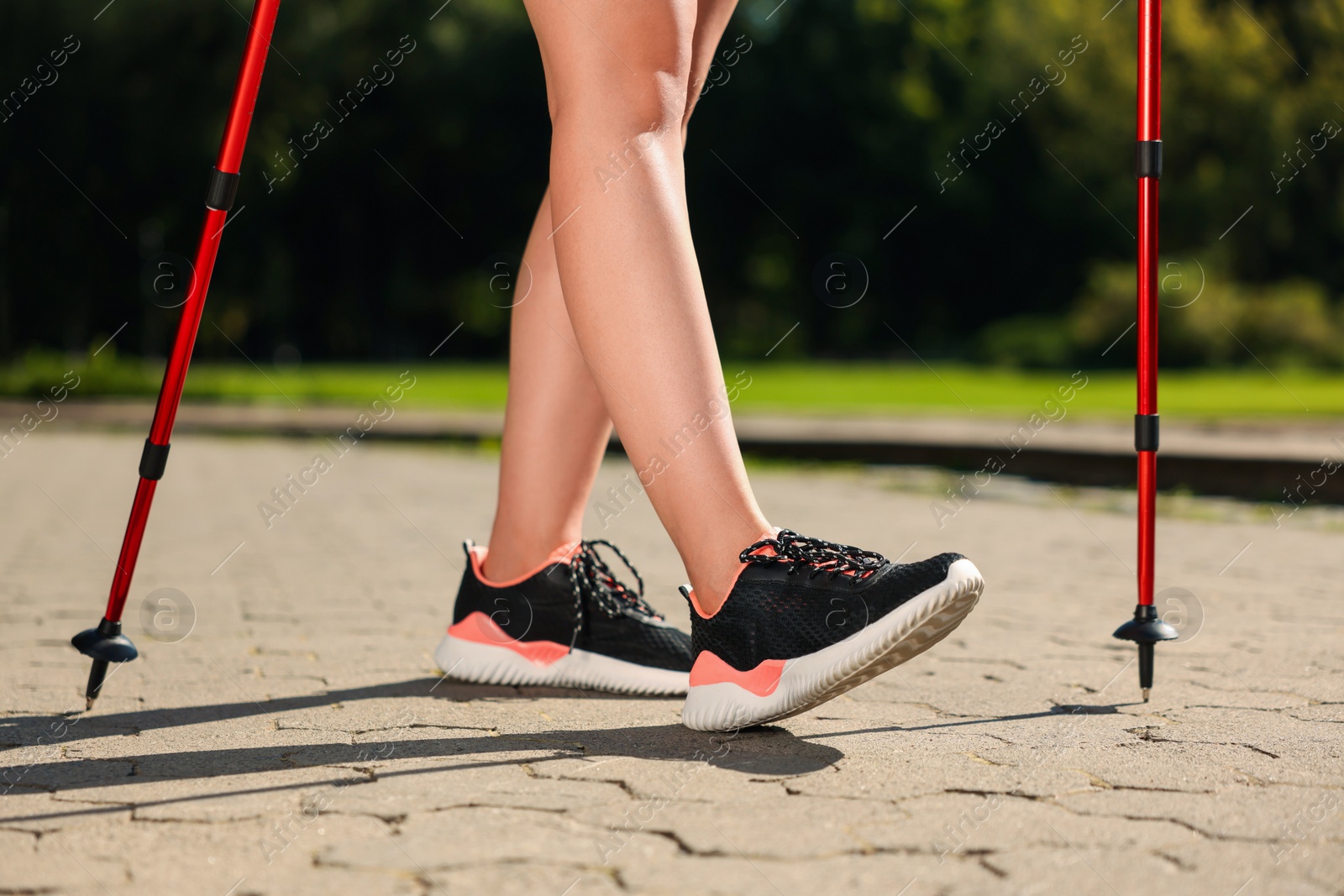 Photo of Woman practicing Nordic walking with poles outdoors on sunny day, closeup