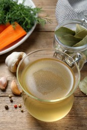 Hot delicious bouillon in glass cup on wooden table, above view