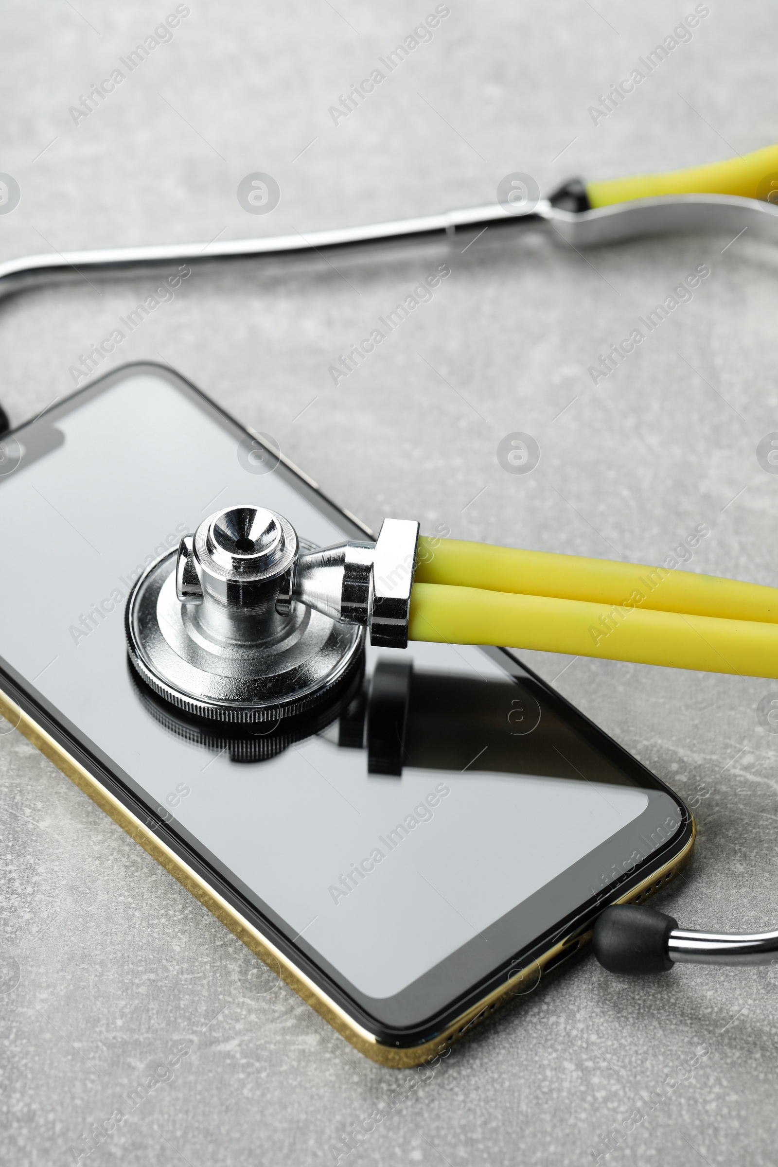 Photo of Stethoscope and modern smartphone on grey table