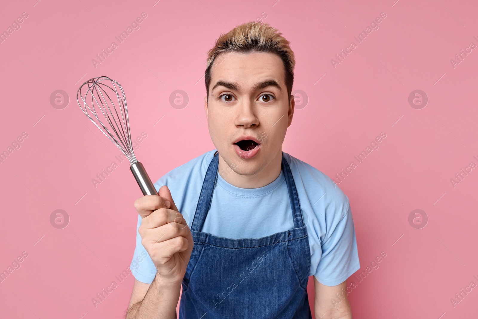 Photo of Portrait of emotional confectioner holding whisk on pink background