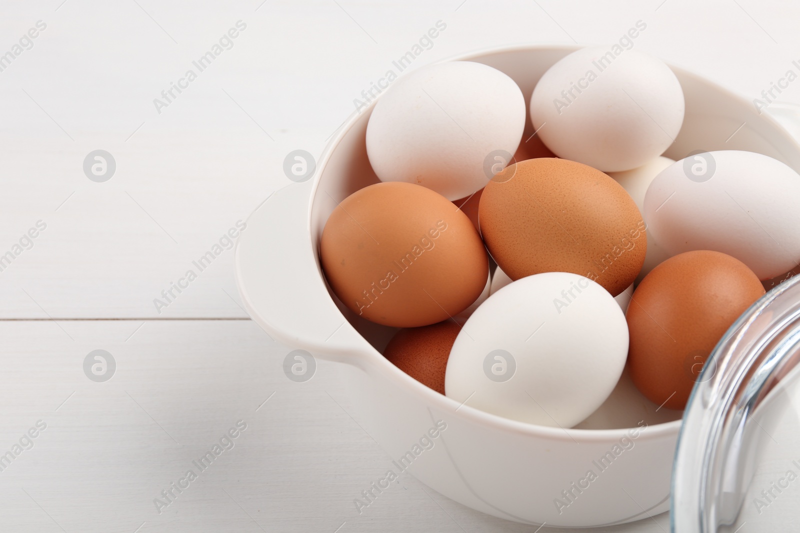 Photo of Unpeeled boiled eggs in saucepan on white wooden table, closeup. Space for text