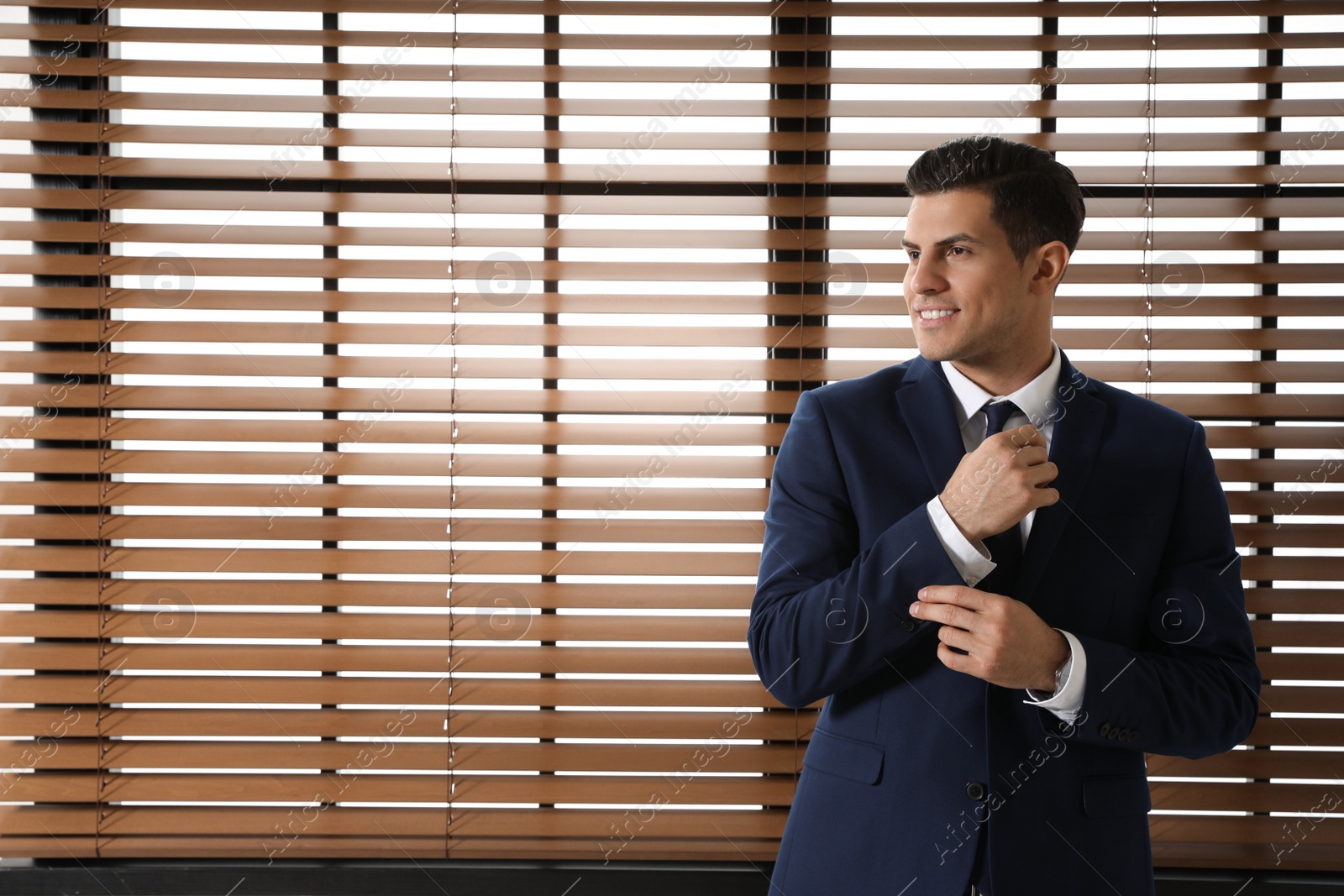 Photo of Portrait of confident businessman at window indoors. Space for text