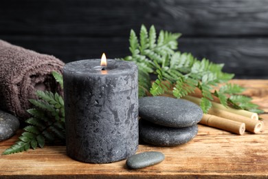 Photo of Composition with burning candle and spa stones on wooden table