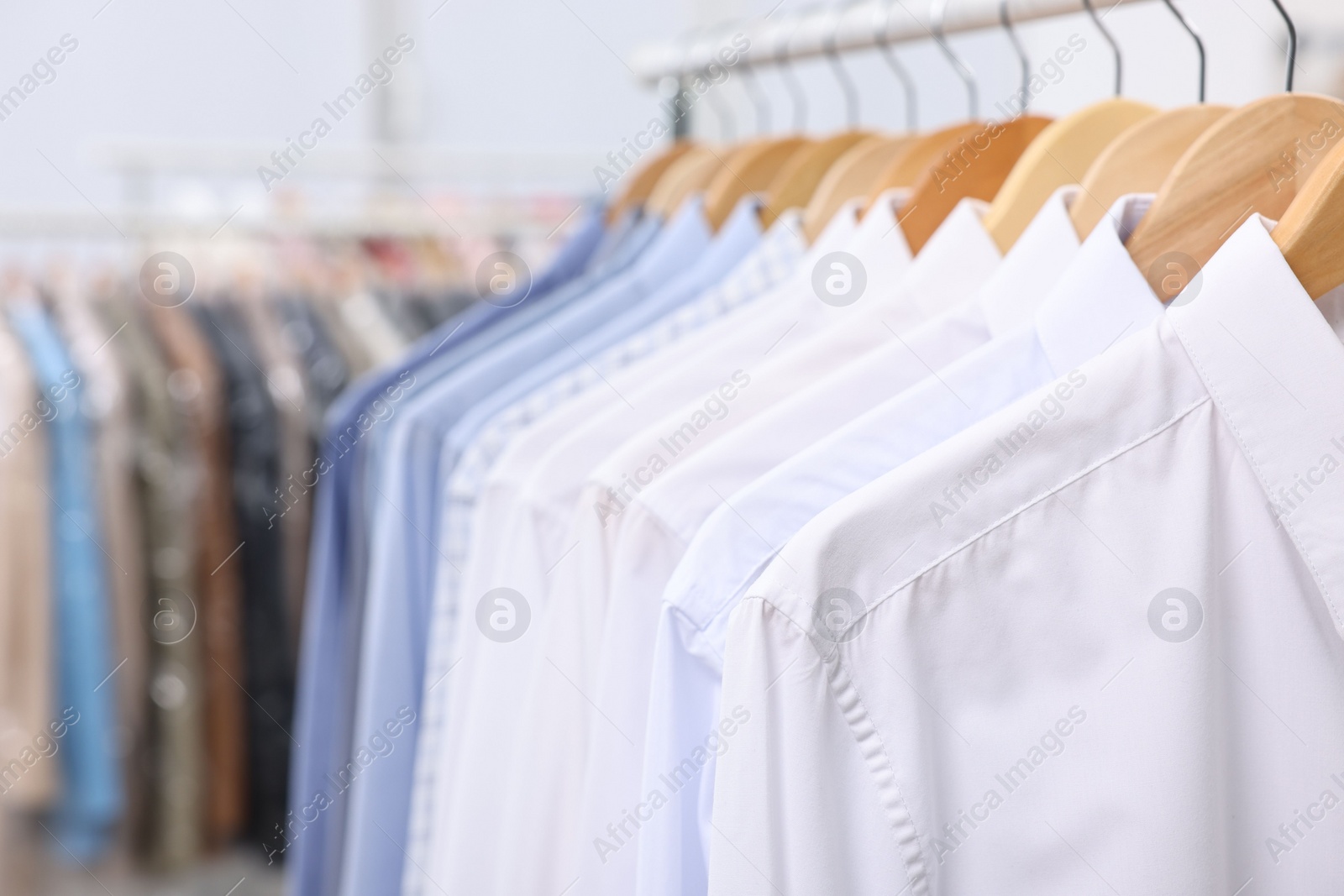 Photo of Dry-cleaning service. Many different clothes hanging on rack indoors, closeup