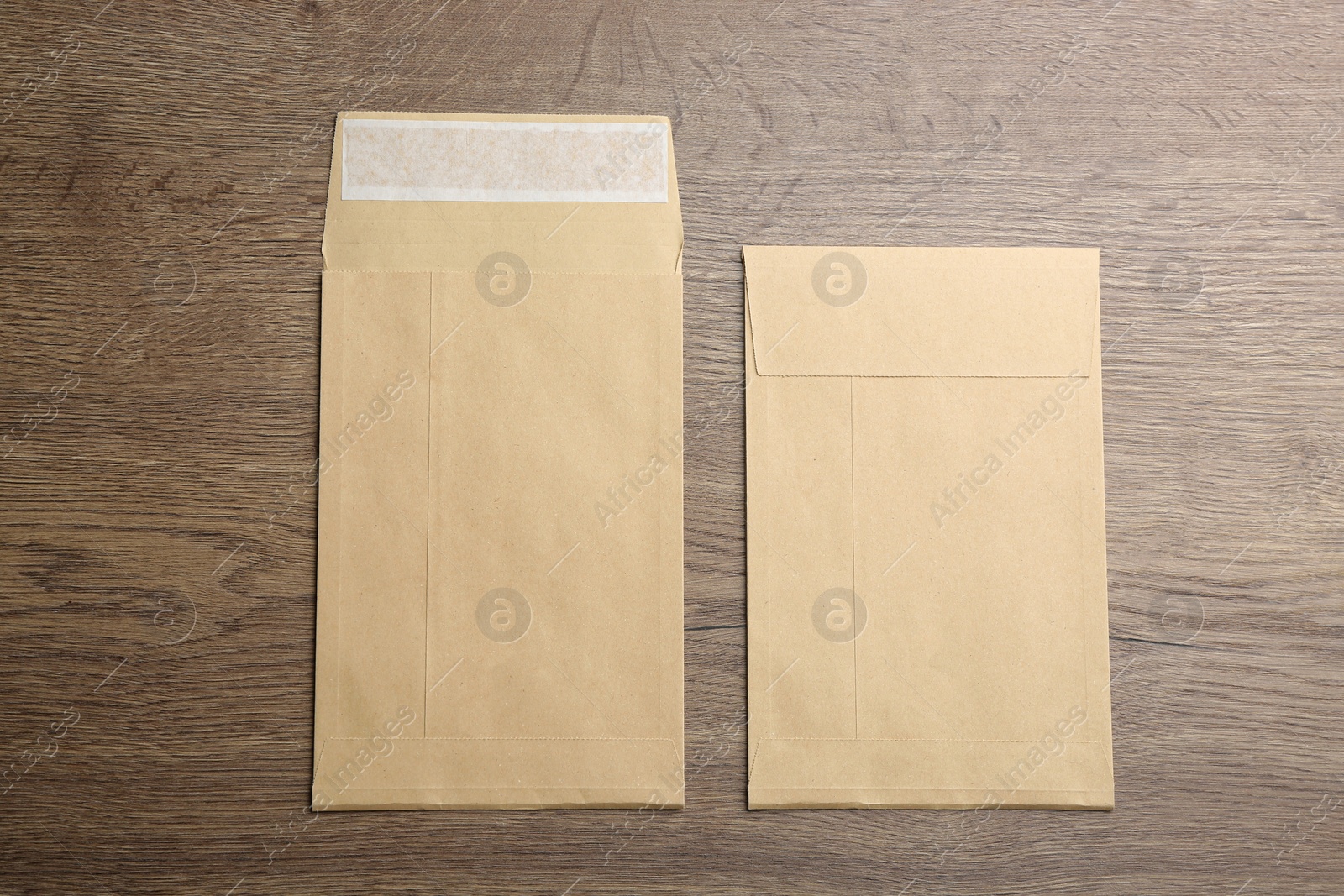 Photo of Kraft paper envelopes on wooden background, flat lay