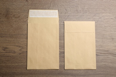 Photo of Kraft paper envelopes on wooden background, flat lay