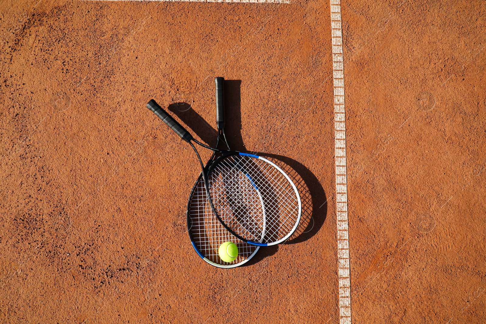 Photo of Tennis ball and rackets on clay court, flat lay