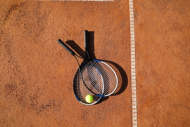 Tennis ball and rackets on clay court, flat lay