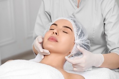 Photo of Professional cosmetologist holding skincare ampoule while working with client in clinic, closeup