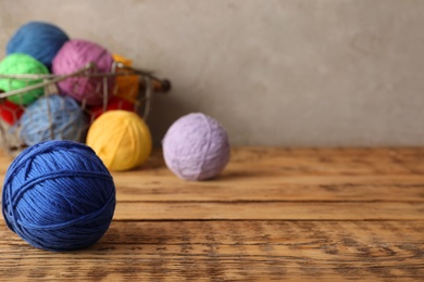 Photo of Colorful woolen yarns on wooden table. Space for text