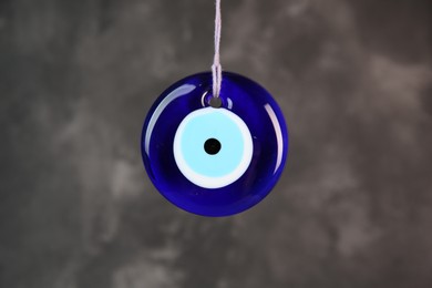 Photo of Evil eye amulet hanging on dark grey background, closeup