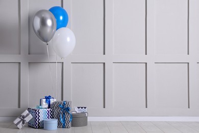 Photo of Many gift boxes and balloons near white wall. Space for text