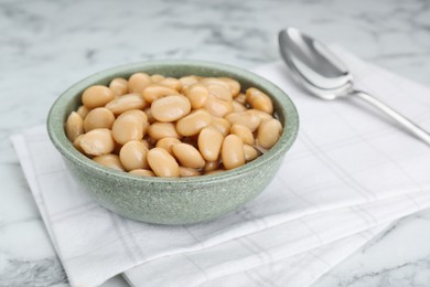 Photo of Bowl of canned kidney beans on white marble table, closeup