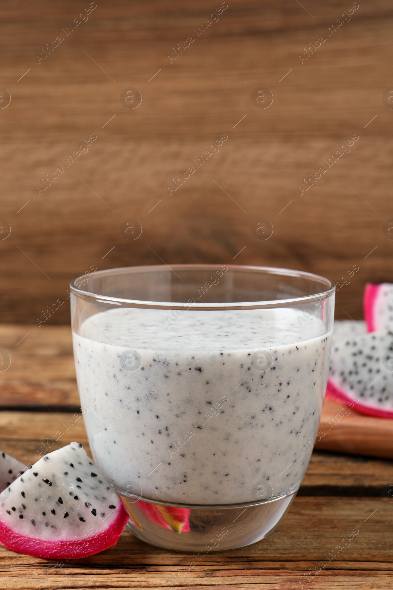 Photo of Glass of tasty pitahaya smoothie and fresh fruit on wooden table
