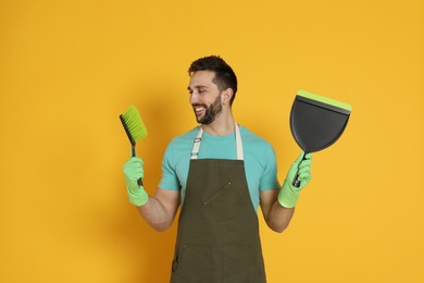 Man with brush and dustpan on orange background