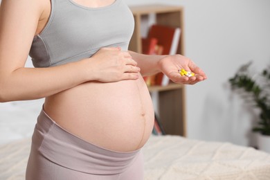 Pregnant woman taking pills at home, closeup