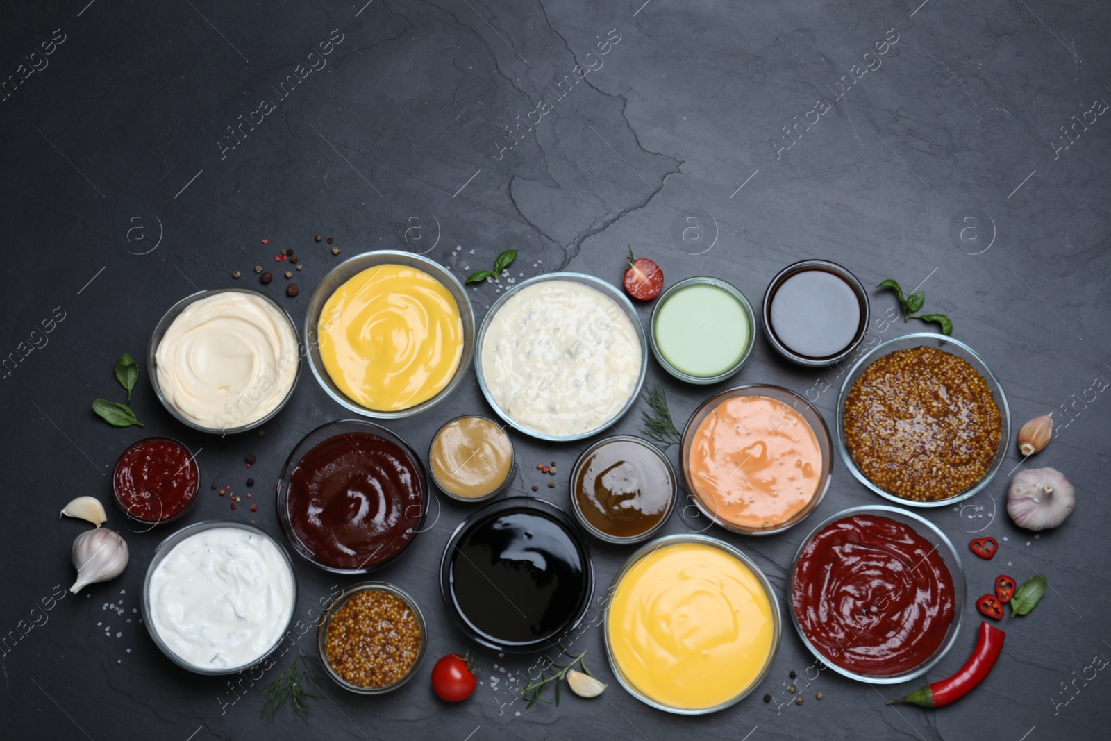 Photo of Many different sauces on black table, flat lay