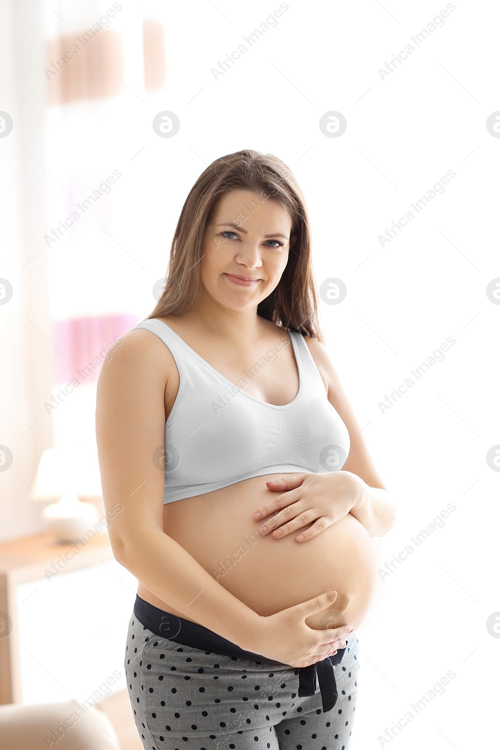 Photo of Pregnant young woman after application of body cream on blurred background