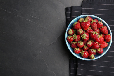 Photo of Delicious ripe strawberries in bowl on black table, flat lay. Space for text