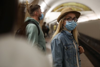 Photo of Young woman in protective mask at subway station, space for text. Public transport