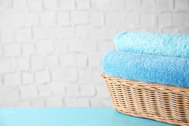 Photo of Wicker basket with clean soft bath towels on blue wooden table. Space for text