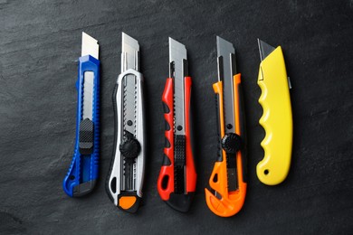 Different utility knives on black table, flat lay