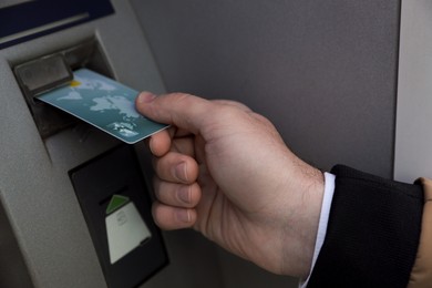 Photo of Man inserting credit card into cash machine, closeup