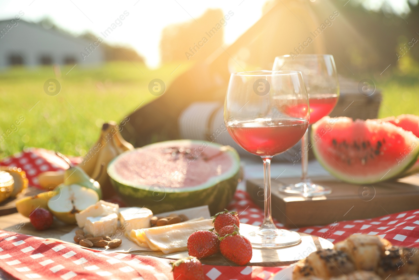 Photo of Picnic blanket with delicious food and drinks outdoors on sunny day, closeup