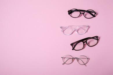 Different stylish glasses on pink background, flat lay. Space for text