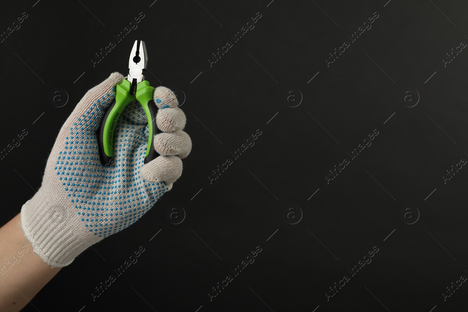 Photo of Man with combination pliers on black background, closeup. Space for text