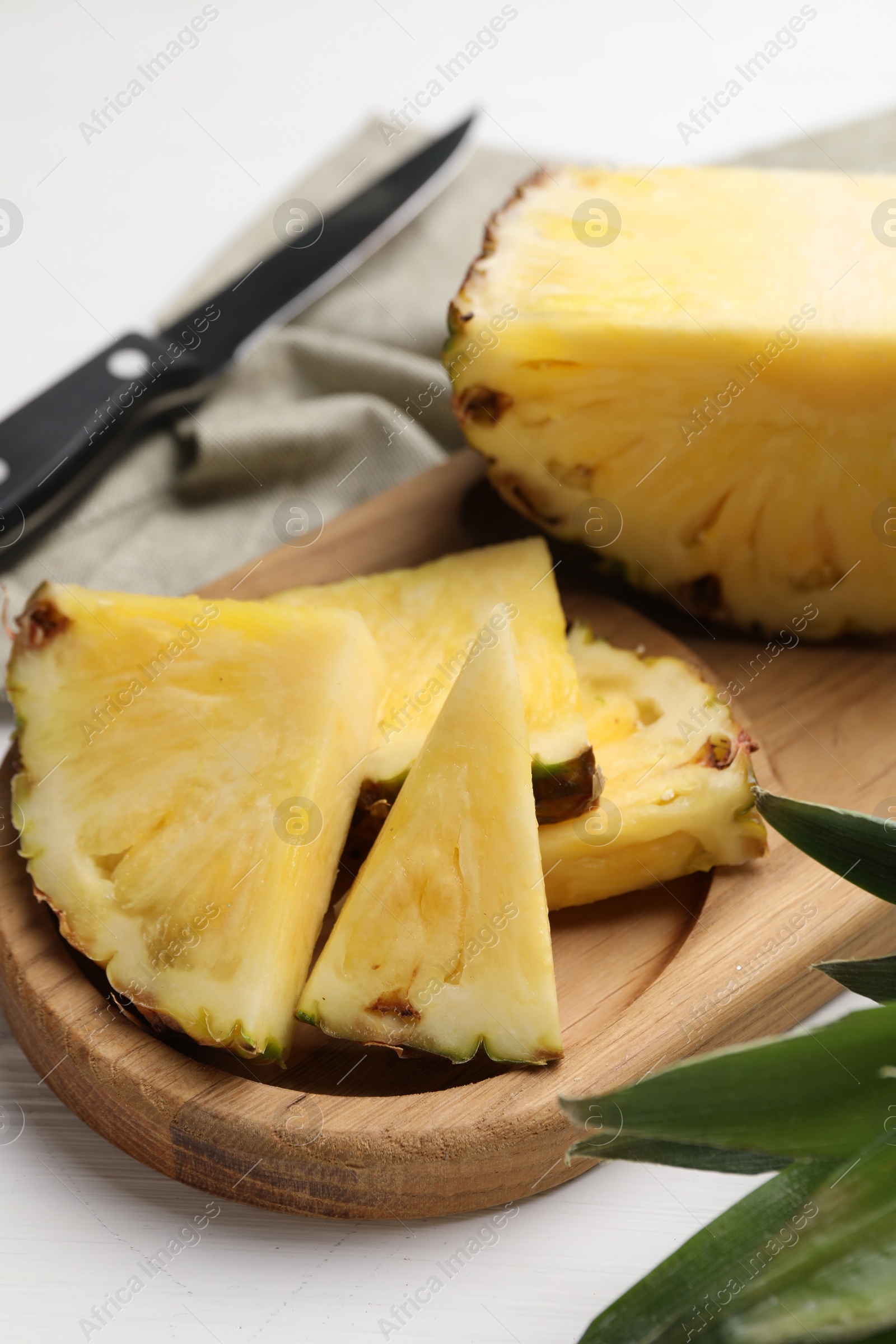 Photo of Slices of ripe juicy pineapple and knife on white table, closeup