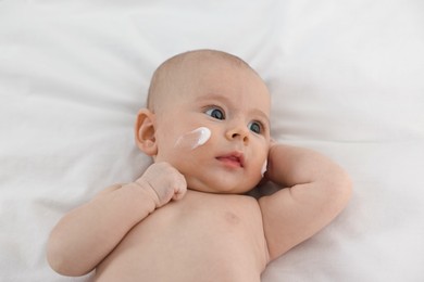 Photo of Cute little baby with cream on face on white blanket