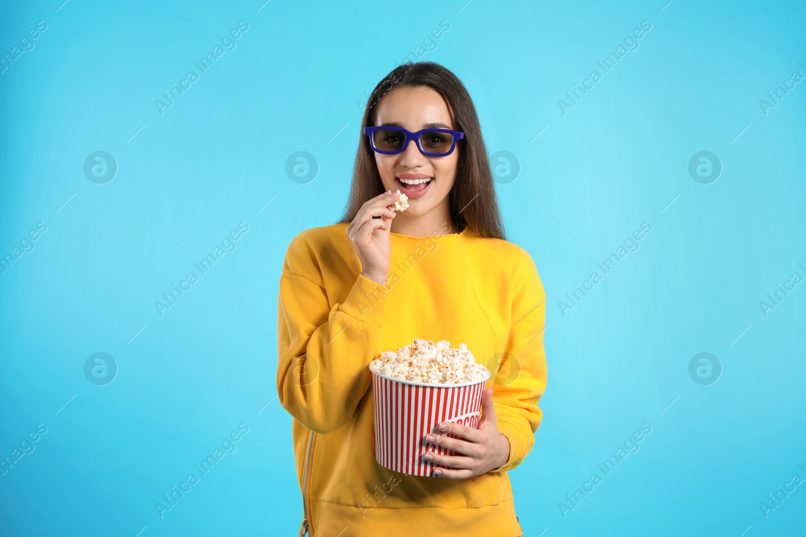 Photo of Woman with 3D glasses and popcorn during cinema show on color background