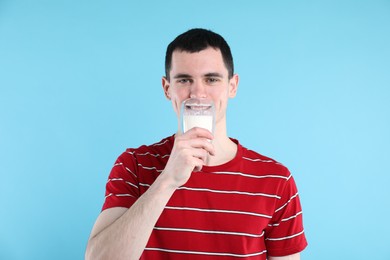 Photo of Milk mustache left after dairy product. Man drinking milk on light blue background