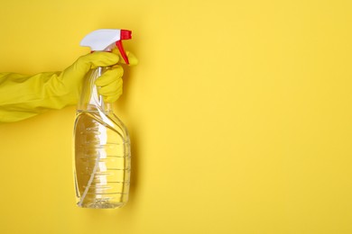 Photo of Woman holding plastic spray bottle on yellow background, closeup. Space for text