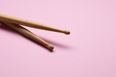 Photo of Two wooden drum sticks on pink background, space for text
