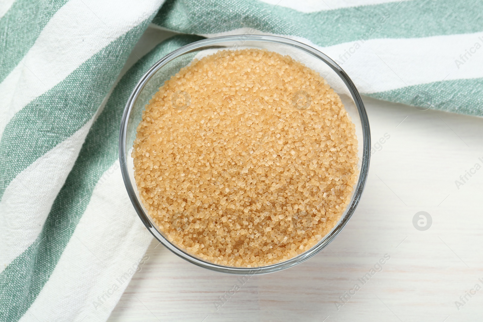 Photo of Brown sugar in glass bowl on white wooden table, top view