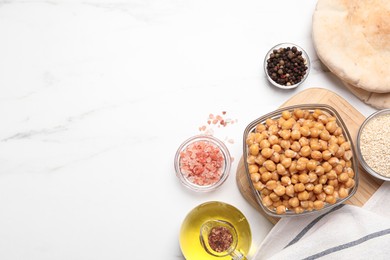 Photo of Delicious chickpeas and different products on white marble table, flat lay with space for text. Hummus ingredients