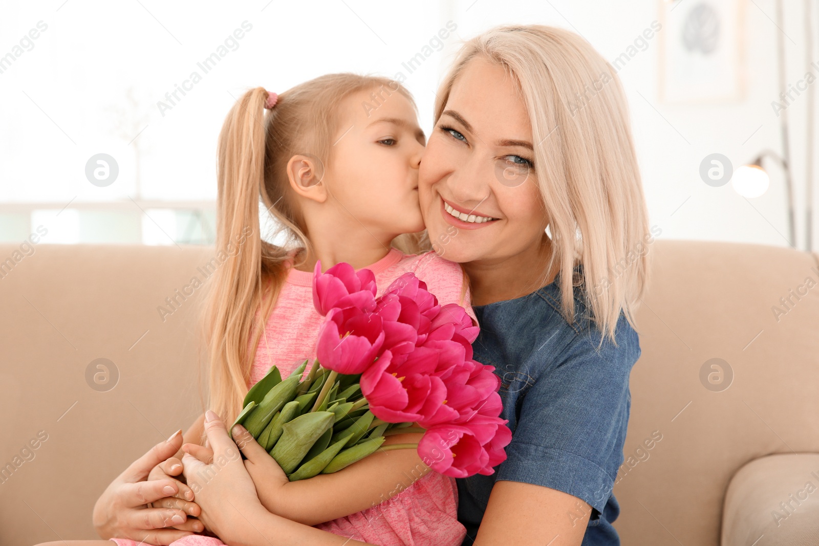 Photo of Happy little girl and her grandmother with tulip bouquet at home