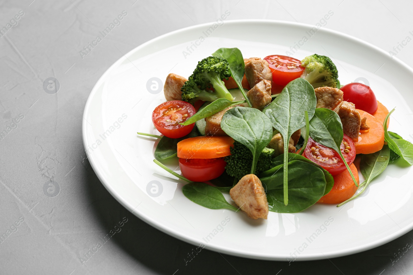 Photo of Delicious fresh chicken salad served on grey table, closeup