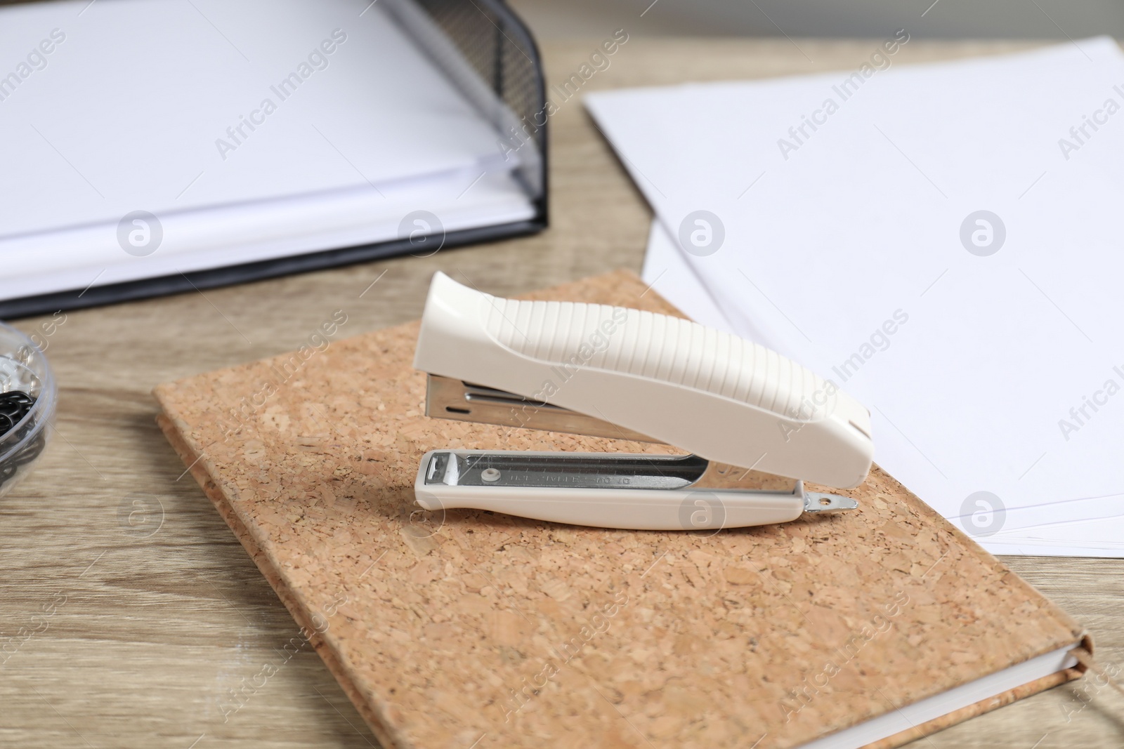 Photo of Stapler, notebook and papers on wooden table, closeup