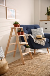 Photo of Stylish living room interior with wooden ladder and comfortable armchair