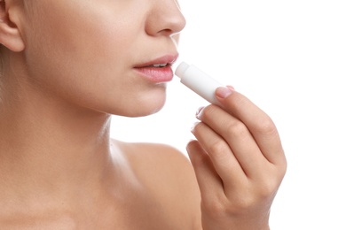 Photo of Young woman with cold sore applying lip balm against white background, closeup