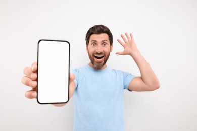 Photo of Surprised man showing smartphone in hand on white background