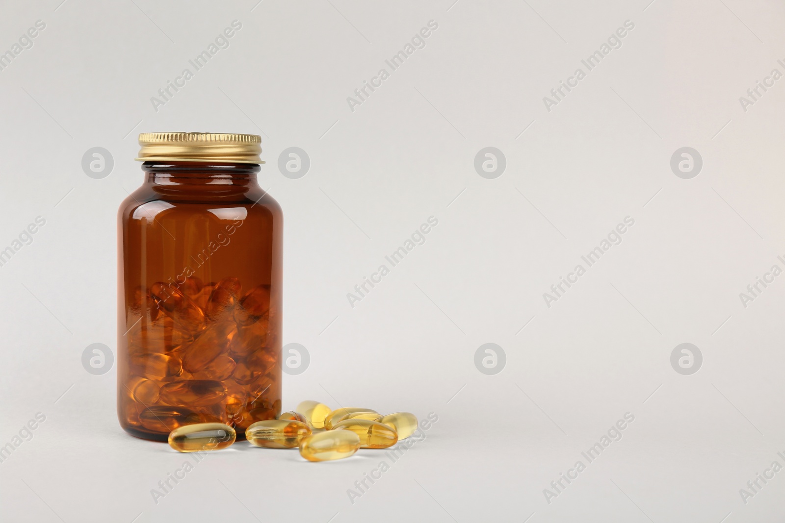 Photo of Jar with vitamin capsules on light grey background, space for text